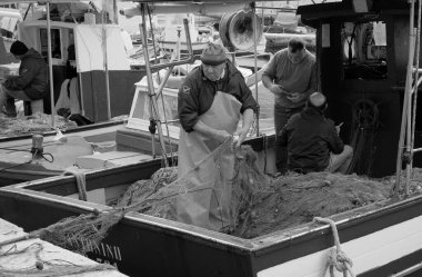 İtalya, Sicilya, Akdeniz, Egadi takımadaları, Favignana Adası (Trapani Eyaleti); 22 Mart 2024, limanda balıkçılar, balıkçılar, balıkçı tekneleri ve ağlar - EDITORIAL