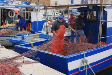 İtalya, Sicilya, Akdeniz, Egadi takımadaları, Favignana Adası (Trapani Eyaleti); 22 Mart 2024, limanda balıkçılar, balıkçılar, balıkçı tekneleri ve ağlar - EDITORIAL