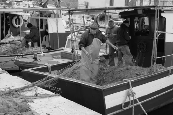 İtalya, Sicilya, Akdeniz, Egadi takımadaları, Favignana Adası (Trapani Eyaleti); 22 Mart 2024, limanda balıkçılar, balıkçılar, balıkçı tekneleri ve ağlar - EDITORIAL