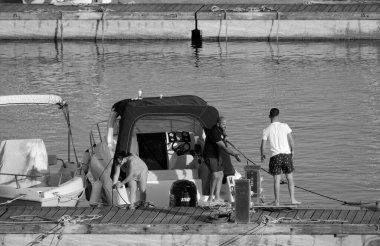 İtalya, Sicilya, Akdeniz, Marina di Ragusa (Ragusa Eyaleti); 26 Mayıs 2024, limanda lüks bir yatta çift - EDITORIAL