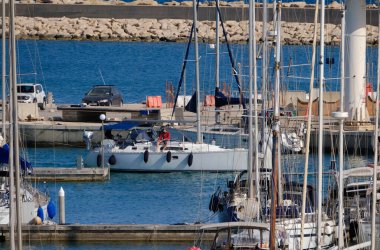 İtalya, Sicilya, Akdeniz, Marina di Ragusa (Ragusa Eyaleti); 28 Mayıs 2024, limandaki bir yelkenli teknesi ve lüks yatlarda erkekler - EDITORIAL