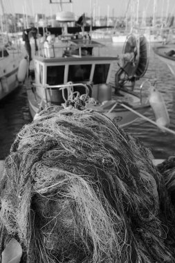 İtalya, Sicilya, Marina di Ragusa (Ragusa Eyaleti), balıkçı ağları, yerel ahşap balıkçı tekneleri ve limanda lüks yatlar