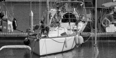 İtalya, Sicilya, Akdeniz, Marina di Ragusa (Ragusa Eyaleti); 6 Haziran 2024, limandaki bir yelkenli teknesinde adam - EDITORIAL