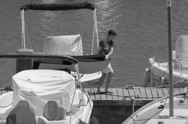 İtalya, Sicilya, Akdeniz, Marina di Ragusa (Ragusa ili); 7 Haziran 2024, limanda insanlar ve motorlu tekneler - EDITORIAL