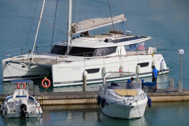 İtalya, Sicilya, Akdeniz, Marina di Ragusa (Ragusa ili); 10 Haziran 2024, limanda bir katamaran yelkenli teknesinde çift - EDITORIAL