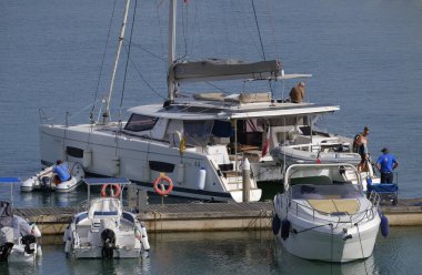 İtalya, Sicilya, Akdeniz, Marina di Ragusa (Ragusa ili); 10 Haziran 2024, limanda bir katamaran yelkenli teknesinde çift - EDITORIAL