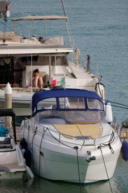 İtalya, Sicilya, Akdeniz, Marina di Ragusa (Ragusa Eyaleti); 20 Haziran 2024, limandaki bir katamaran yelkenli teknesinde kadın - EDITORIAL