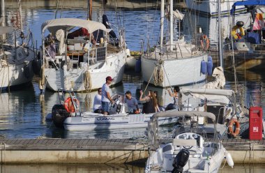 İtalya, Sicilya, Akdeniz, Marina di Ragusa (Ragusa Eyaleti); 28 Haziran 2024, limandaki kauçuk bir teknede insanlar - EDITORIAL