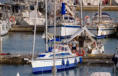 İtalya, Sicilya, Akdeniz, Marina di Ragusa (Ragusa Eyaleti); 30 Haziran 2024, limandaki bir yelkenli teknesinde adam - EDITORIAL