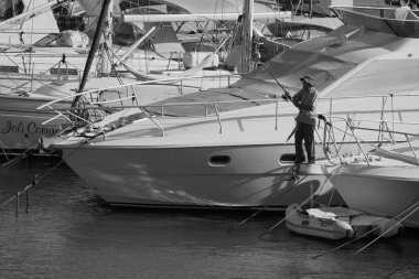 İtalya, Sicilya, Akdeniz, Marina di Ragusa (Ragusa Eyaleti); 2 Temmuz 2024, limanda lüks bir yatta balık tutan adam - EDITORIAL