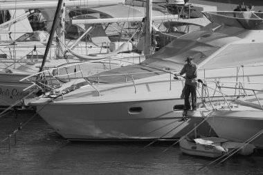 İtalya, Sicilya, Akdeniz, Marina di Ragusa (Ragusa Eyaleti); 2 Temmuz 2024, limanda lüks bir yatta balık tutan adam - EDITORIAL
