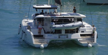 İtalya, Sicilya, Akdeniz, Marina di Ragusa (Ragusa Eyaleti); 5 Temmuz 2024, limandaki katamaran yelkenli teknesinde insanlar - EDITORIAL