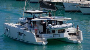 İtalya, Sicilya, Akdeniz, Marina di Ragusa (Ragusa Eyaleti); 5 Temmuz 2024, limandaki katamaran yelkenli teknesinde insanlar - EDITORIAL