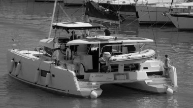 İtalya, Sicilya, Akdeniz, Marina di Ragusa (Ragusa Eyaleti); 5 Temmuz 2024, limandaki katamaran yelkenli teknesinde insanlar - EDITORIAL