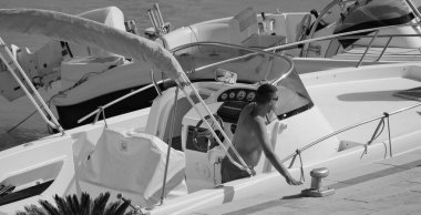 İtalya, Sicilya, Akdeniz, Marina di Ragusa (Ragusa Eyaleti); 6 Temmuz 2024, limanda lüks bir yatta bir adam - EDITORIAL