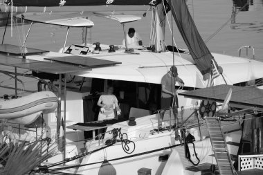 İtalya, Sicilya, Akdeniz, Marina di Ragusa (Ragusa Eyaleti); 6 Temmuz 2024, limandaki katamaran yelkenli teknesinde insanlar - EDITORIAL