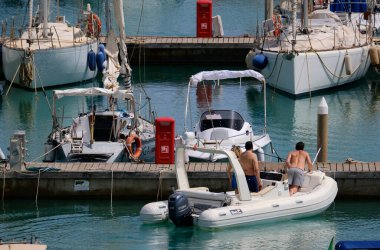 İtalya, Sicilya, Akdeniz, Marina di Ragusa (Ragusa ili); 7 Temmuz 2024, limandaki kauçuk bir teknede insanlar - EDITORIAL