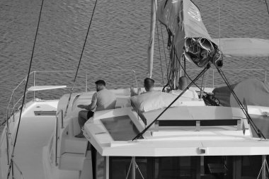 İtalya, Sicilya, Akdeniz, Marina di Ragusa (Ragusa Eyaleti); 8 Temmuz 2024, limandaki katamaran yelkenli teknesinde erkekler - EDITORIAL