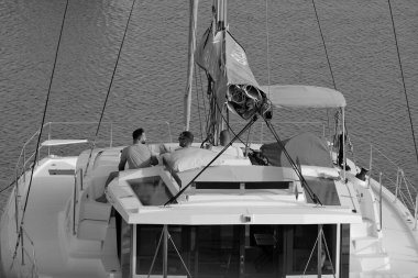 İtalya, Sicilya, Akdeniz, Marina di Ragusa (Ragusa Eyaleti); 8 Temmuz 2024, limandaki katamaran yelkenli teknesinde erkekler - EDITORIAL