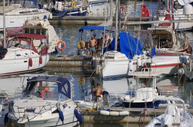 İtalya, Sicilya, Akdeniz, Marina di Ragusa (Ragusa Eyaleti); 11 Temmuz 2024, limandaki insanlar, motorlu tekneler ve lüks yatlar - EDITORIAL