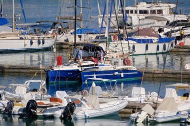 İtalya, Sicilya, Akdeniz, Marina di Ragusa (Ragusa ili); 11 Temmuz 2024, limandaki bir trimaran yelkenli teknesi ve lüks yatlarda yaşayan insanlar - EDITORIAL