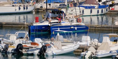 Italy, Sicily, Mediterranean Sea, Marina di Ragusa (Ragusa Province); 11 July 2024, people on a trimaran sailing boat and luxury yachts in the port - EDITORIAL clipart