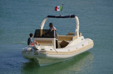 İtalya, Sicilya, Akdeniz, Marina di Ragusa (Ragusa Eyaleti); 12 Temmuz 2024, limandaki büyük bir kauçuk teknede insanlar - EDITORIAL