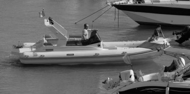 İtalya, Sicilya, Akdeniz, Marina di Ragusa (Ragusa Eyaleti); 12 Temmuz 2024, büyük bir kauçuk bot ve limandaki lüks yatlarda yaşayan insanlar - EDITORIAL