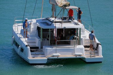 İtalya, Sicilya, Akdeniz, Marina di Ragusa (Ragusa ili); 13 Temmuz 2024, limandaki katamaran yelkenli teknesinde erkekler - EDITORIAL