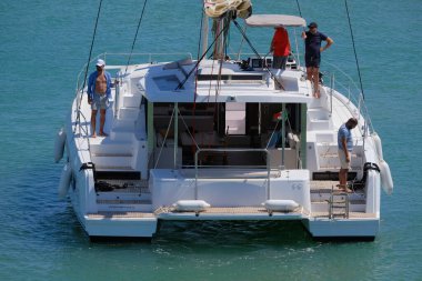 İtalya, Sicilya, Akdeniz, Marina di Ragusa (Ragusa ili); 13 Temmuz 2024, limandaki katamaran yelkenli teknesinde erkekler - EDITORIAL