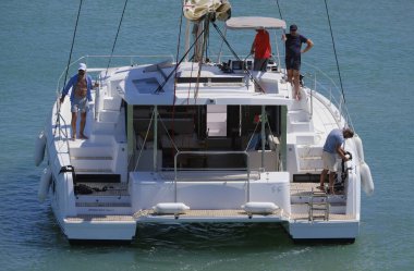 İtalya, Sicilya, Akdeniz, Marina di Ragusa (Ragusa ili); 13 Temmuz 2024, limandaki katamaran yelkenli teknesinde erkekler - EDITORIAL