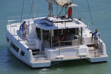 İtalya, Sicilya, Akdeniz, Marina di Ragusa (Ragusa ili); 13 Temmuz 2024, limandaki katamaran yelkenli teknesinde erkekler - EDITORIAL