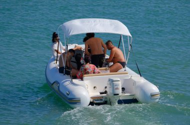 İtalya, Sicilya, Akdeniz, Marina di Ragusa (Ragusa Eyaleti); 13 Temmuz 2024, limandaki kauçuk bir teknede insanlar - EDITORIAL