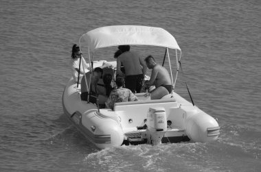 İtalya, Sicilya, Akdeniz, Marina di Ragusa (Ragusa Eyaleti); 13 Temmuz 2024, limandaki kauçuk bir teknede insanlar - EDITORIAL