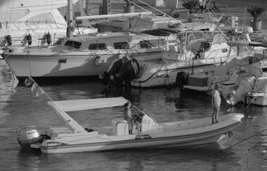 İtalya, Sicilya, Akdeniz, Marina di Ragusa (Ragusa ili); 13 Temmuz 2024, limanda büyük bir kauçuk teknede erkekler - EDITORIAL