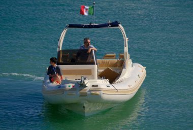 İtalya, Sicilya, Akdeniz, Marina di Ragusa (Ragusa Eyaleti); 12 Temmuz 2024, limandaki büyük bir kauçuk teknede insanlar - EDITORIAL