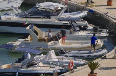 İtalya, Sicilya, Akdeniz, Marina di Ragusa (Ragusa Eyaleti); 12 Temmuz 2024, limandaki büyük bir kauçuk teknede insanlar - EDITORIAL