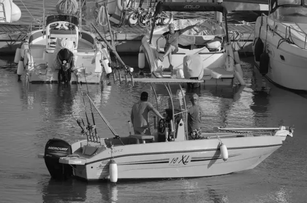 İtalya, Sicilya, Akdeniz, Marina di Ragusa (Ragusa Eyaleti); 19 Temmuz 2024, bir motorlu tekne ve limanda lüks yatlarda balıkçılık yapan balıkçılar - EDITORIAL