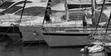 İtalya, Sicilya, Akdeniz, Marina di Ragusa (Ragusa ili); 21 Temmuz 2024, limandaki lüks yatlarda erkekler - EDITORIAL