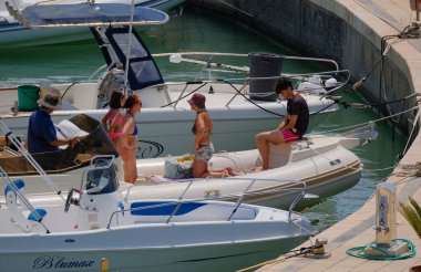 İtalya, Sicilya, Akdeniz, Marina di Ragusa (Ragusa ili); 27 Temmuz 2024, limandaki kauçuk bir teknede insanlar - EDITORIAL