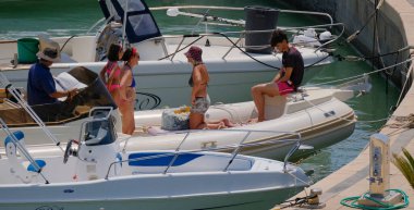 İtalya, Sicilya, Akdeniz, Marina di Ragusa (Ragusa ili); 27 Temmuz 2024, limandaki kauçuk bir teknede insanlar - EDITORIAL