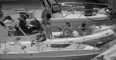 İtalya, Sicilya, Akdeniz, Marina di Ragusa (Ragusa ili); 27 Temmuz 2024, limandaki kauçuk bir teknede insanlar - EDITORIAL