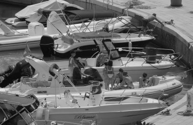 İtalya, Sicilya, Akdeniz, Marina di Ragusa (Ragusa ili); 27 Temmuz 2024, limandaki kauçuk bir teknede insanlar - EDITORIAL