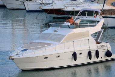 İtalya, Sicilya, Akdeniz, Marina di Ragusa (Ragusa Eyaleti); 27 Temmuz 2024, limanda lüks bir yatta bir adam - EDITORIAL