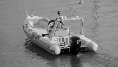 İtalya, Sicilya, Akdeniz, Marina di Ragusa (Ragusa Eyaleti); 30 Temmuz 2024, limanda kauçuk bir tekne ve lüks yatlarda bir çift - EDITORIAL