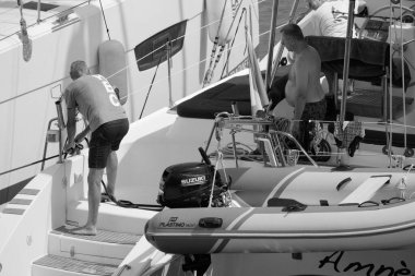 İtalya, Sicilya, Akdeniz, Marina di Ragusa (Ragusa Eyaleti); 5 Ağustos 2024, limandaki katamaran yelkenli teknesinde erkekler - EDITORIAL