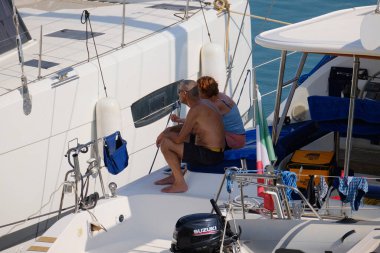 İtalya, Sicilya, Akdeniz, Marina di Ragusa (Ragusa Eyaleti); 5 Ağustos 2024, limanda bir katamaran yelkenli teknesinde çift