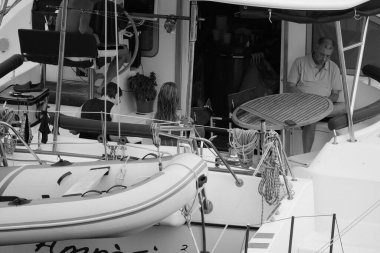 İtalya, Sicilya, Akdeniz, Marina di Ragusa (Ragusa Eyaleti); 5 Ağustos 2024, limandaki katamaran yelkenli teknesinde insanlar - EDITORIAL