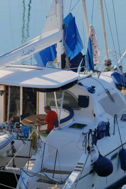 İtalya, Sicilya, Akdeniz, Marina di Ragusa (Ragusa ili); 6 Ağustos 2024, limanda bir katamaran yelkenli teknesinde çift - EDITORIAL