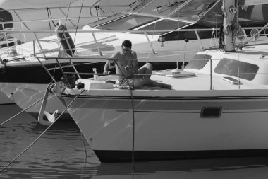 İtalya, Sicilya, Akdeniz, Marina di Ragusa (Ragusa Eyaleti); 6 Ağustos 2024, limandaki bir yelkenli teknesinde adam - EDITORIAL